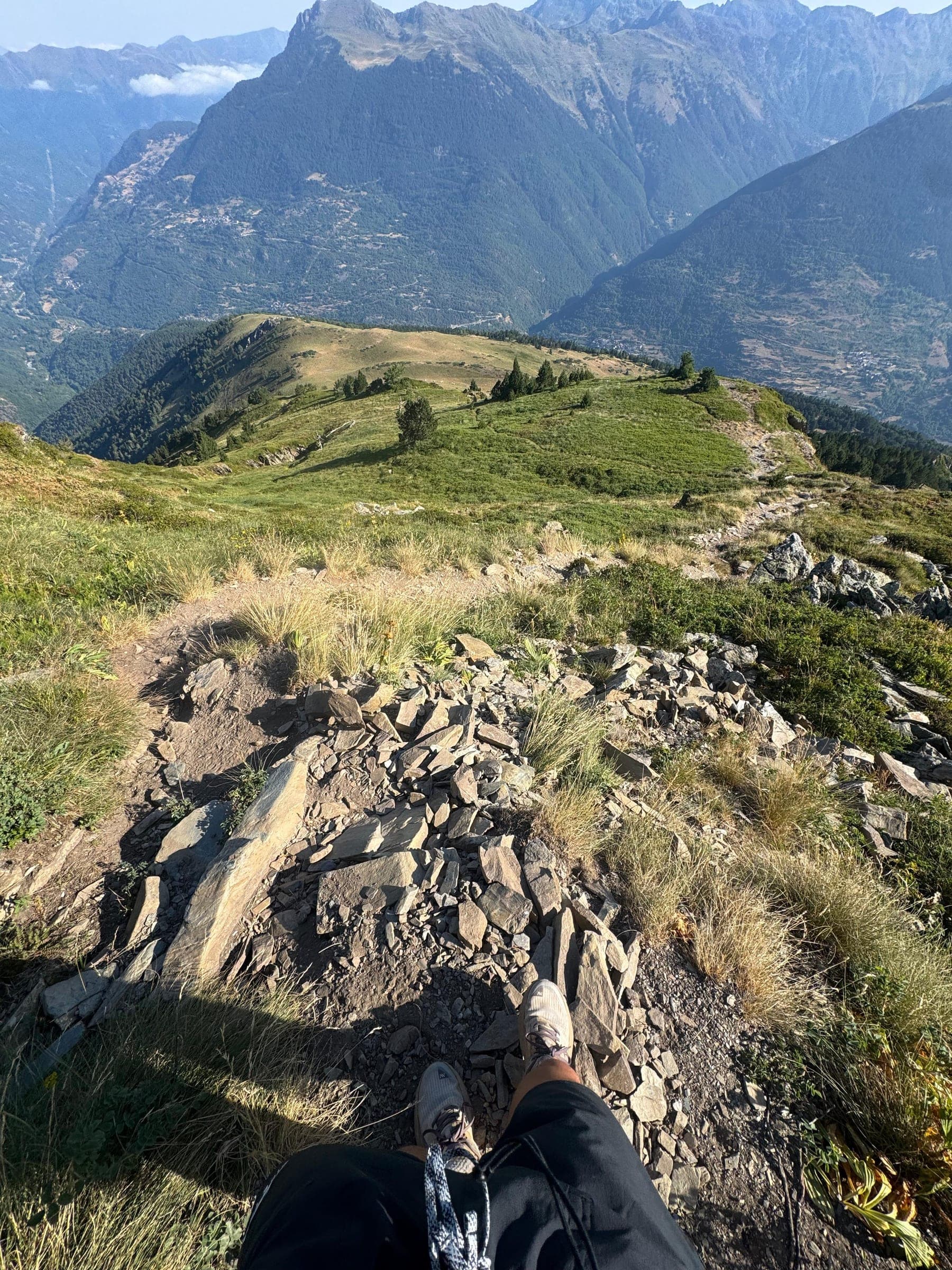Pies sobre una cresta rocosa con pueblos del Val d'Aran al fondo